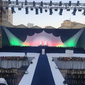 Escenario de boda con decoración elegante, incluyendo flores y sillas blancas organizadas para los invitados.