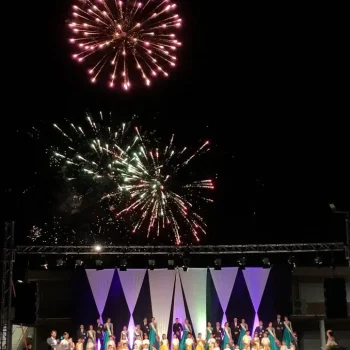 Fuegos artificiales brillan en el cielo, realzando la atmósfera de un espectáculo en un escenario al aire libre.