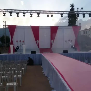 Escenario accesible con rampa, sillas organizadas y alfombra rosa, listo para recibir a los asistentes.