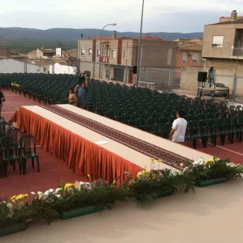 Escenario accesible con rampa, mesa amplia y sillas organizadas para la audiencia.