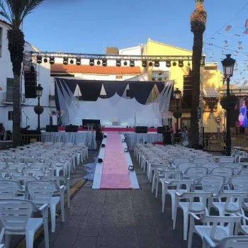 Escenario con sillas alineadas y una rampa decorada con alfombra rosa.