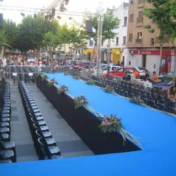 Escenario con rampa cubierto de una alfombra azul, preparado para un evento o presentación.