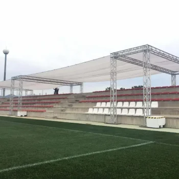 Vista de un estadio con gradas y un toldo que proporciona sombra a los espectadores.