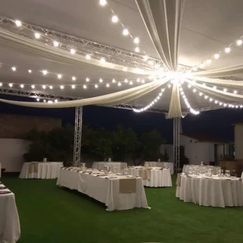 Celebración de boda con mesas vestidas de blanco y luces de cadena que añaden un toque romántico al entorno.