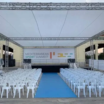 Interior de una carpa amplia, con sillas organizadas y alfombra de color azul.