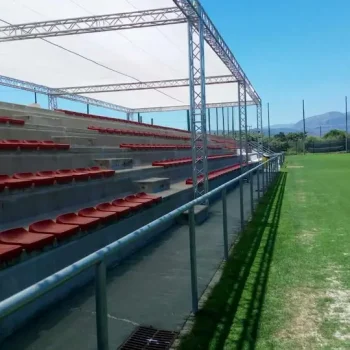Estadio con asientos rojos y un campo iluminado, listo para un evento deportivo.