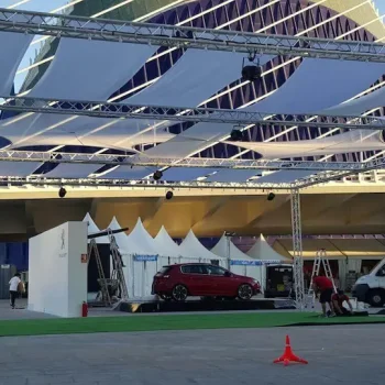 Automóvil bajo una estructura de carpa, situado frente a un edificio.