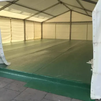 Carpa grande blanca con un suelo de color verde, adecuada para reuniones o celebraciones.