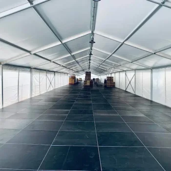 Gran carpa blanca con suelo negro, utilizada para eventos al aire libre.