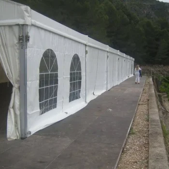 Una carpa blanca con una persona caminando a su lado en un entorno al aire libre.