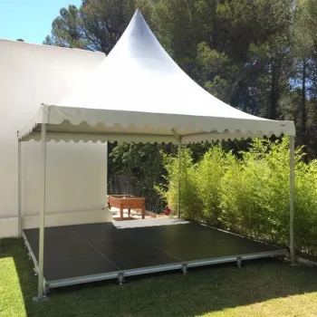 Carpa blanca con un escenario negro en el interior, preparado para un evento o presentación.