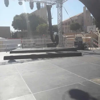 Escenario amplio con una tarima y un potente foco de luz, preparado para una actuación o evento especial.