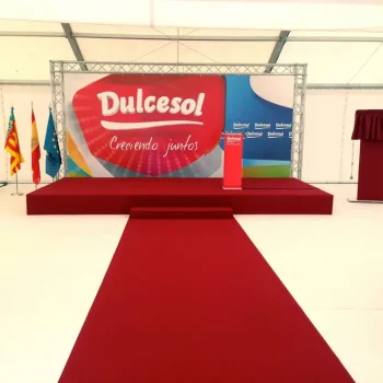 Tarima con una alfombra roja colocada frente a una gran carpa, lista para un evento de la empresa Dulcesol.