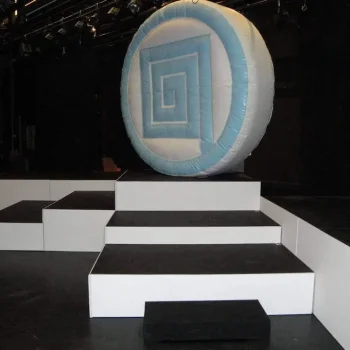 Escenario con una gran bola inflable y escalones, creando un ambiente festivo para un evento o espectáculo.