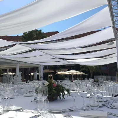 Recepción de boda al aire libre con carpas blancas y telas elásticas decorativas.
