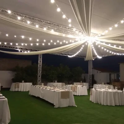 Recepción de boda con manteles blancos y luces de cadena decorativas.