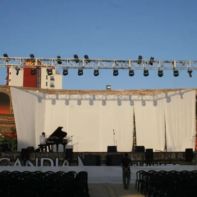 Escenario con fondo blanco y varias sillas dispuestas para un evento o presentación.