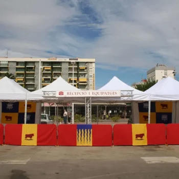 Valla de aluminio cubierta con tela decorativa que presenta la bandera de España en un evento al aire libre.