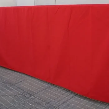 Valla de aluminio cubierta con tela roja, apoyada sobre un soporte de madera.