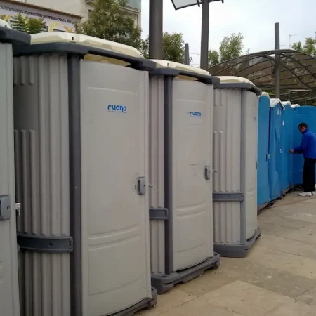 Fila de WC portátiles, destacando el logo de Ruano Group, en un evento al aire libre.