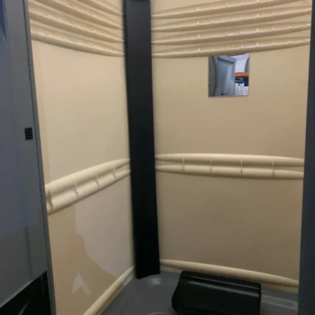 Baño con inodoro químico y espejo, mostrando un ambiente funcional.